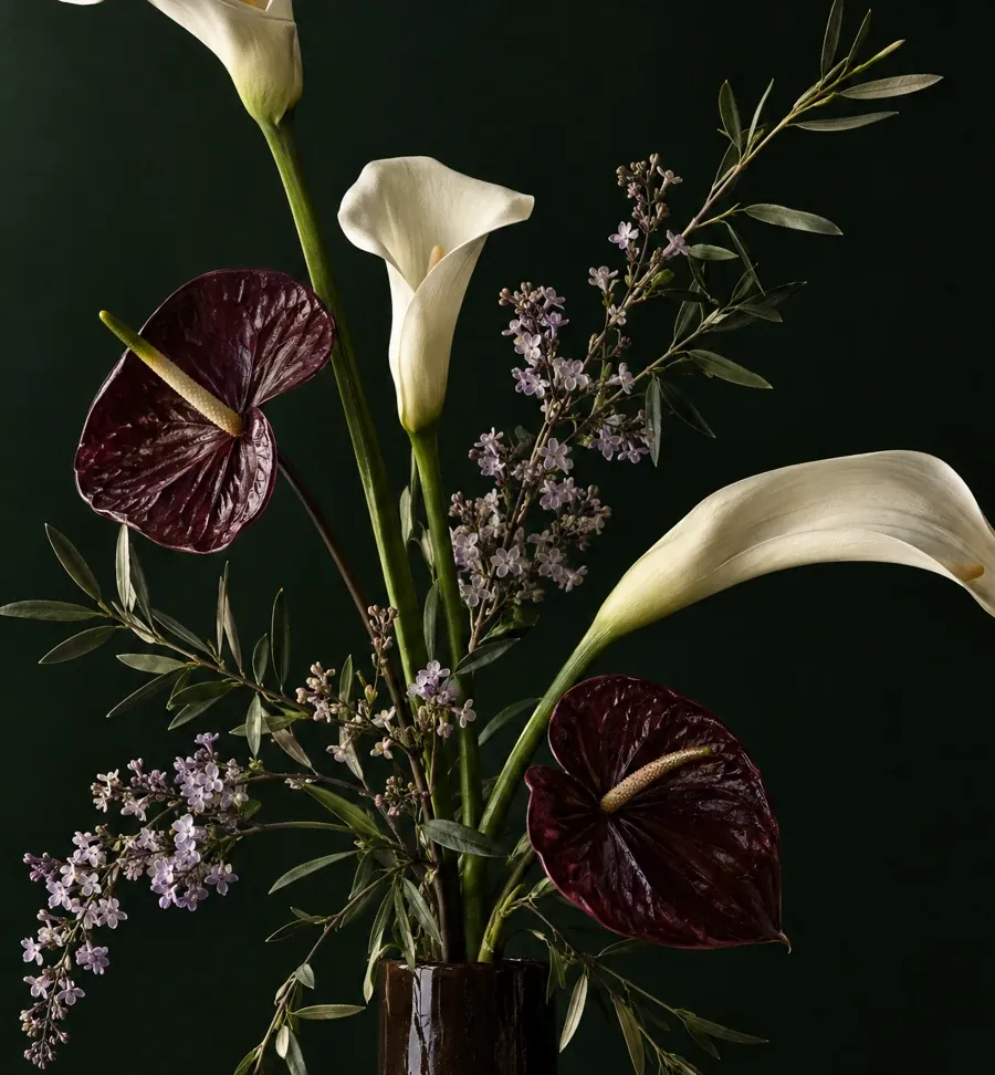 Close-up of ivory calla petals, burgundy anthuriums and lilac sprays